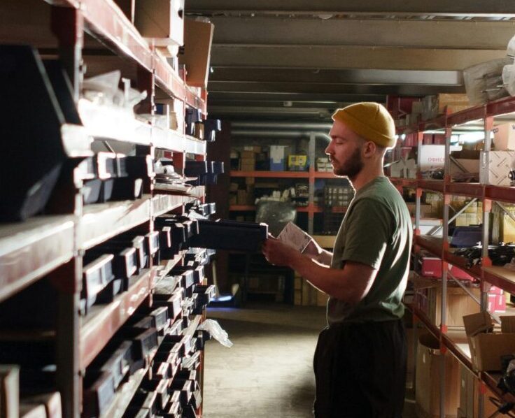 A warehouse worker sorting items on shelves in an organized storage space.