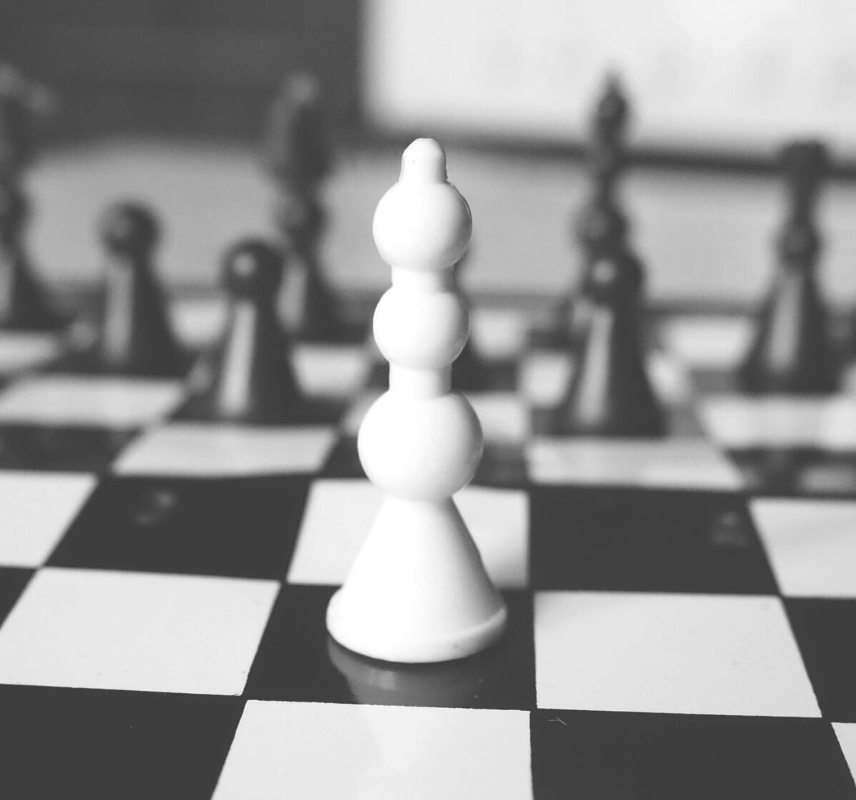 Black and white chessboard with a prominent white pawn in focus, symbolizing strategy and focus.